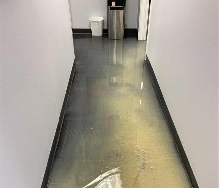 Water and sand on a business floor from a slab leak
